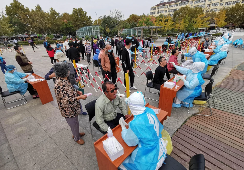 Nhân viên y tế lấy mẫu xét nghiệm COVID-19 cho người dân tại thành phố Thanh Đảo, tỉnh Sơn Đông, Trung Quốc ngày 13/10/2020. (Ảnh: AFP/TTXVN)