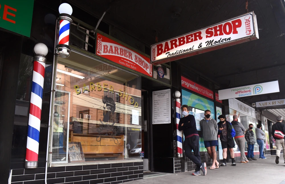 Người dân xếp hàng bên ngoài một tiệm cắt tóc tại Melbourne, Australia, ngày 19/10/2020. (Ảnh: AFP/TTXVN)