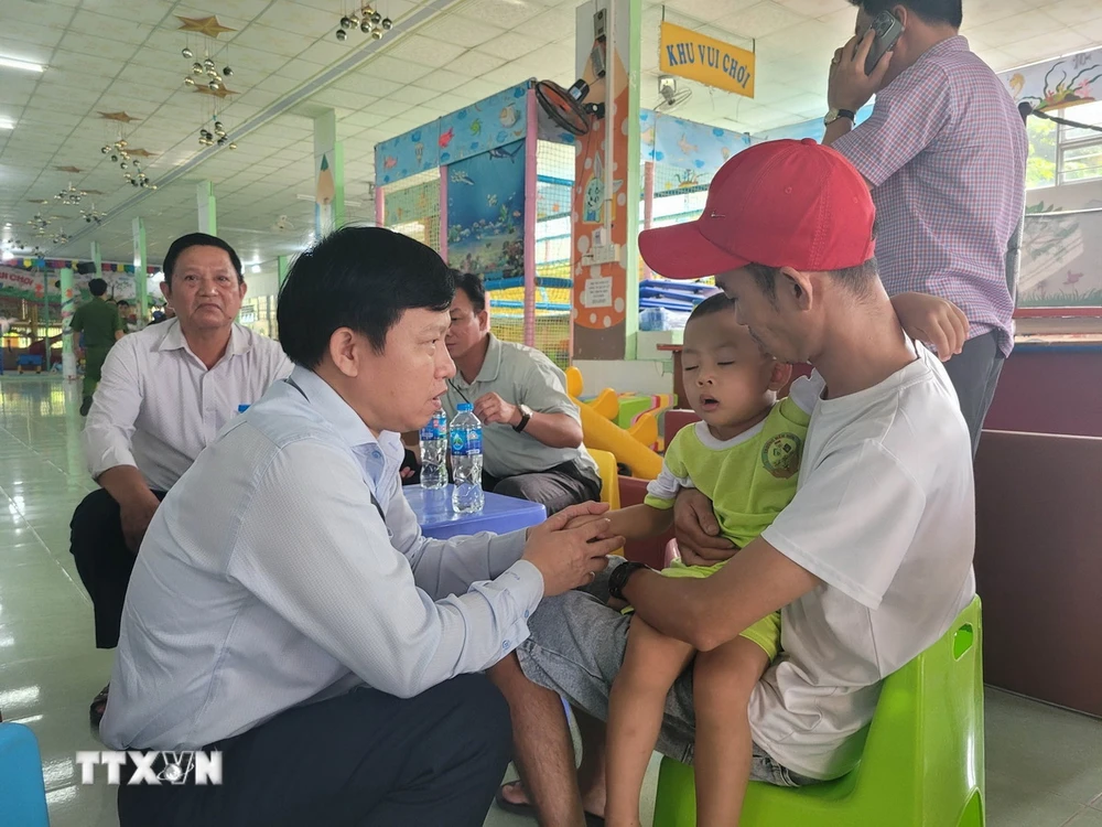Tiến sỹ Lê Quang Trí, Giám đốc Sở Giáo dục và Đào tạo tỉnh Tiền Giang (trái) thăm hỏi cháu bé vừa được giải cứu. (Ảnh: Minh Trí/TTXVN)