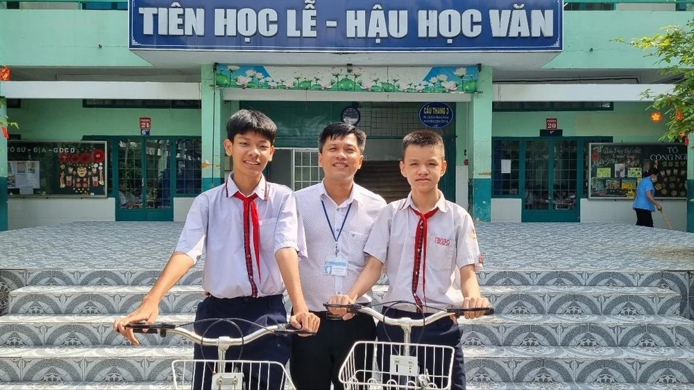 Em Lê Nhật Hảo (bên trái) và Chiêu Bình Sâm (bên phải), chụp ảnh với thầy Hiệu trưởng trường Trung học Cơ sở An Lạc, quận Bình Thạnh, Thành phố Hồ Chí Minh. (Nguồn: Yonhap News)