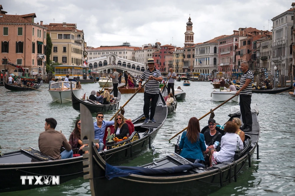 Khách du lịch đi thuyền gondola tại Venice, Italy. (Ảnh: AFP/TTXVN)