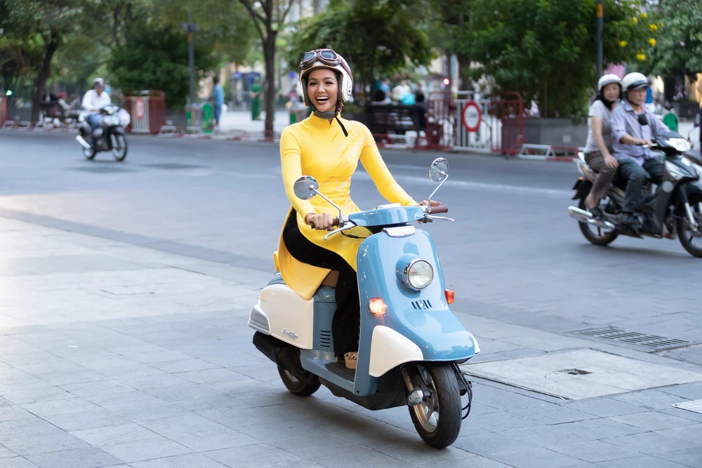 Hoa hậu H’Hen Niê khiến khán giả bất ngờ và thích thú khi mặc áo dài, tự lái chiếc xe máy kiểu dáng cổ điển trên phố. (Ảnh: Thiên An/Vietnam+)