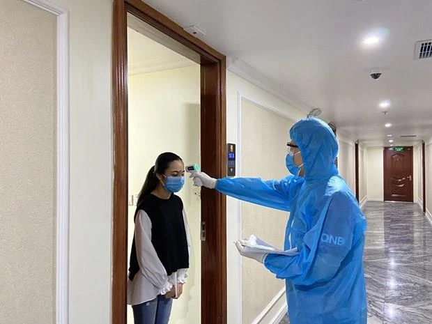 Cán bộ y tế của thành phố Hạ Long kiểm tra thân nhiệt cho khách cách ly y tế tại khách sạn Thái Sơn. (Nguồn: Báo Quảng Ninh)