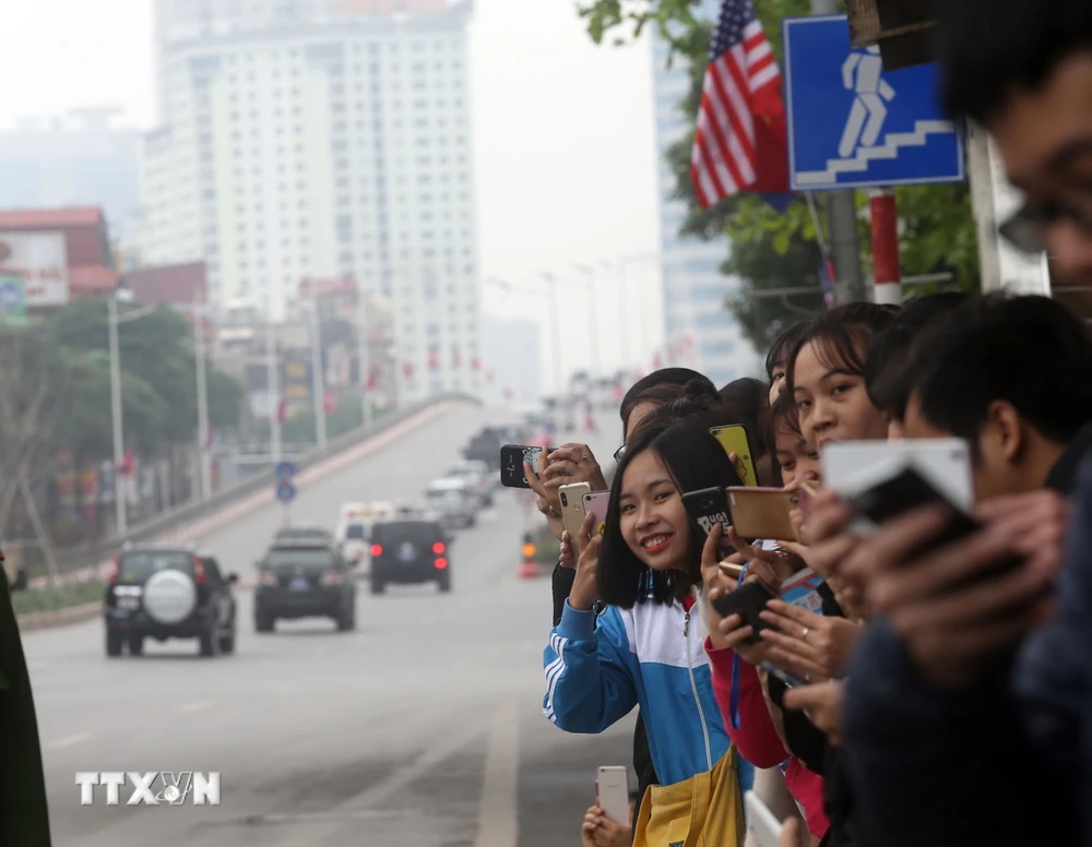 Người dân đứng trên phố Trần Duy Hưng đón đoàn xe của Tổng thống Mỹ Donald Trump đi qua. (Ảnh: Huy Hùng/TTXVN)