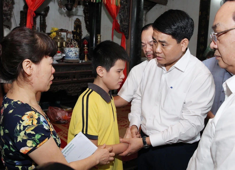 Chủ tịch UBND thành phố Hà Nội Nguyễn Đức Chung thăm hỏi, động viên gia đình chị Lê Thị Thu Hà. (Ảnh: Lâm Khánh/TTXVN)