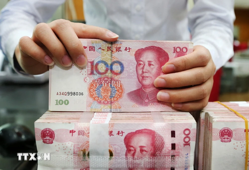 Kiểm tiền mệnh giá 100 nhân dân tệ tại ngân hàng ở tỉnh Giang Tô, Trung Quốc. (Ảnh: AFP/TTXVN)