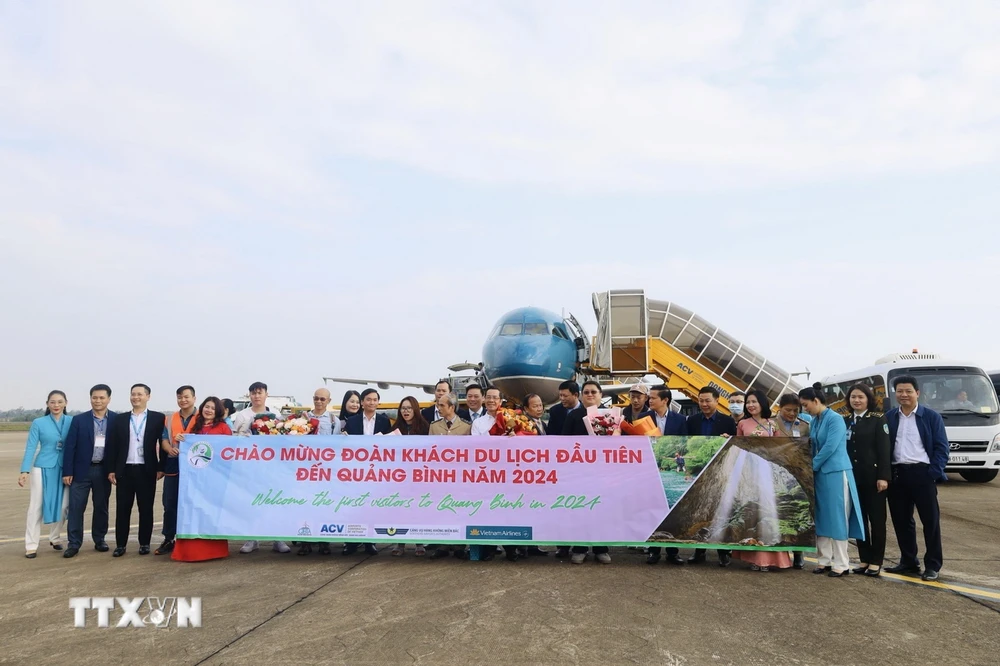 Lãnh đạo Sở Du lịch tỉnh Quảng Bình tặng hoa những du khách đến tỉnh đầu tiên trong năm 2024. (Ảnh: Công Thành/TTXVN)