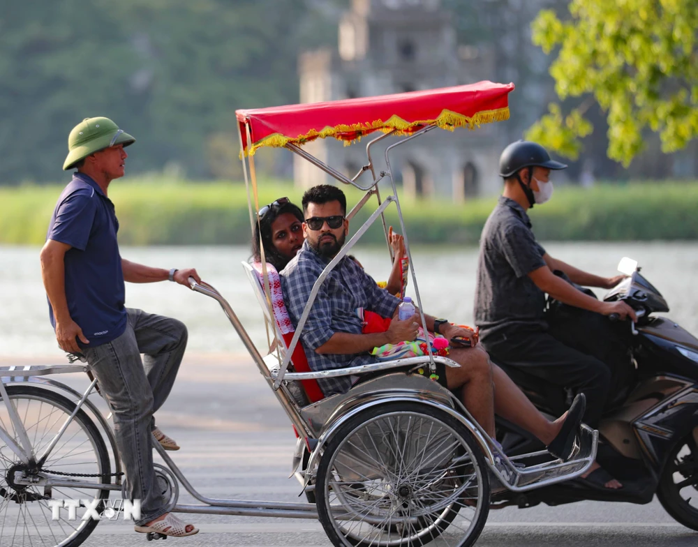 Khách du lịch quốc tế trên xe xích lô tham quan Hà Nội trong thời tiết đẹp. (Nguồn: TTXVN)