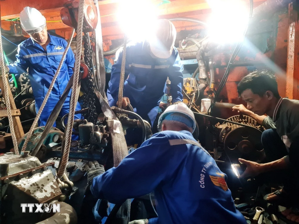 Cán bộ kỹ thuật Trung tâm Dịch vụ Hậu cần-Kỹ thuật đảo Trường Sa tích cực sửa chữa sự cố máy tàu cho ngư dân. (Ảnh: TTXVN phát)