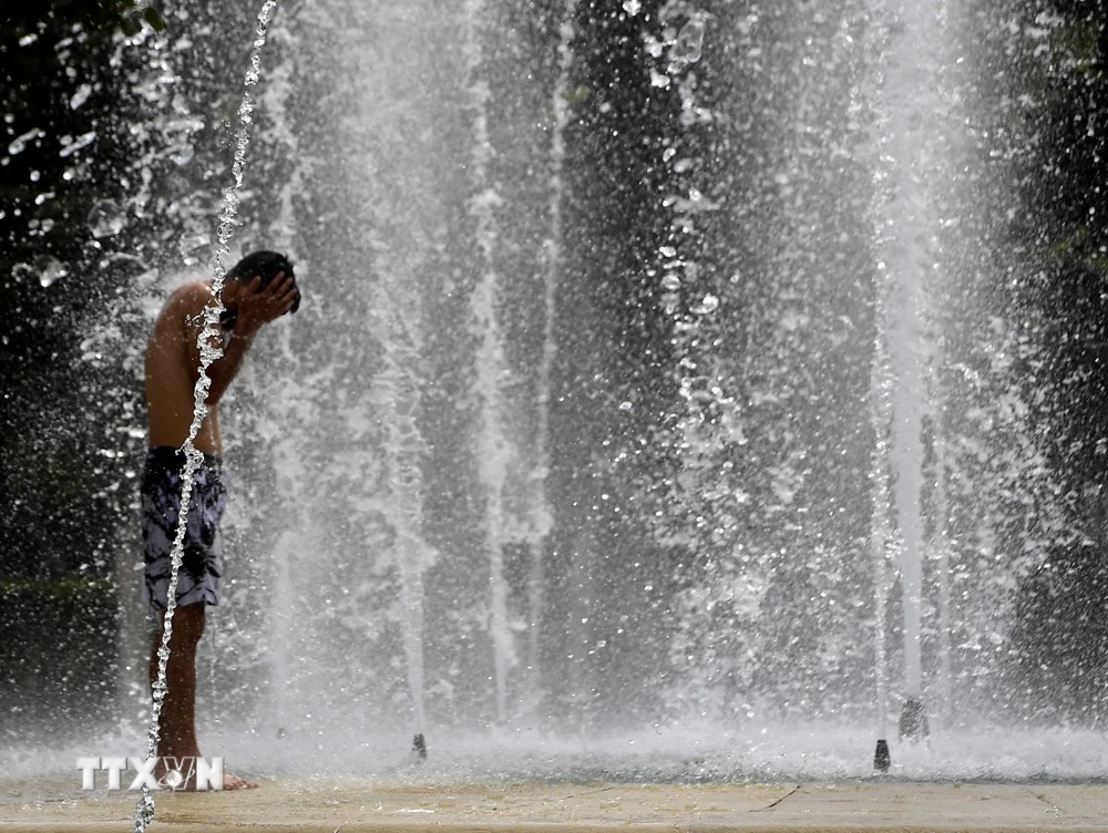 Người dân làm mát tại một đài phun nước ở Seville, Tây Ban Nha. (Ảnh: AFP/TTXVN)