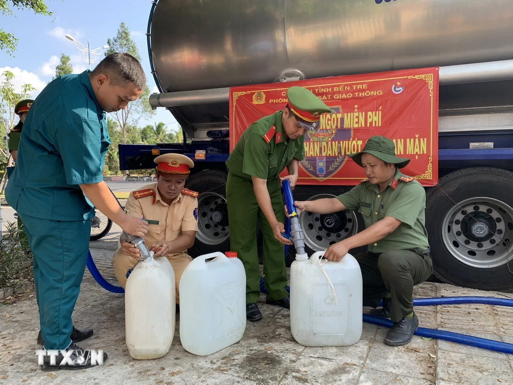 Cán bộ, chiến sỹ Phòng Cảnh sát Giao thông Công an tỉnh Bến Tre cùng các đơn vị liên quan cấp nước ngọt cho người dân. (Ảnh: TTXVN phát)
