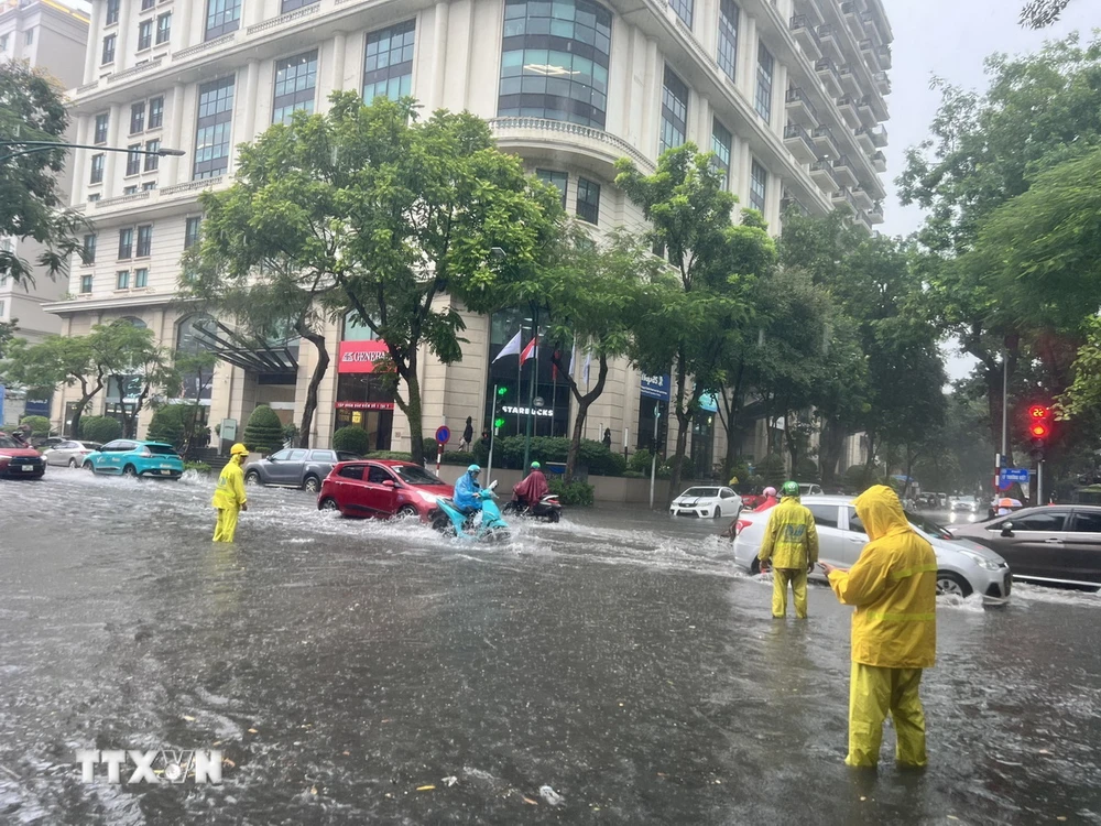 Lực lượng chức năng ứng trực tiêu thoát nước trên đường Lý Thường Kiệt, quận Hoàn Kiếm. (Ảnh: TTXVN phát)