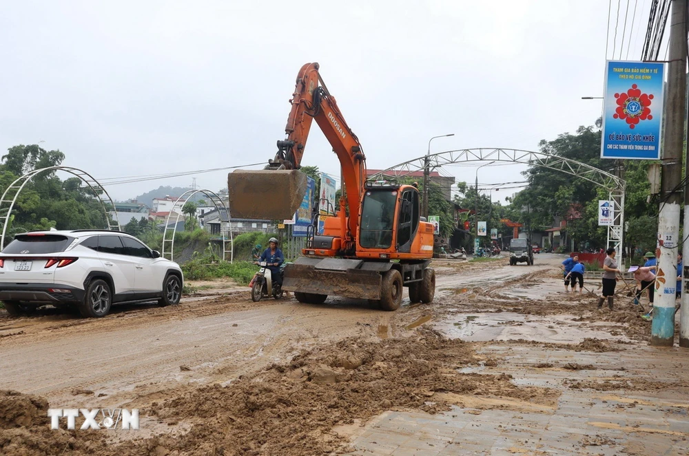 Thành phố Hà Giang huy động các lực lượng và phương tiện dọn dẹp tuyến đường bị ngập sâu. (Ảnh: TTXVN phát)