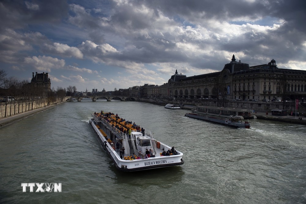 Các thuyền chở khách du lịch di chuyển trên sông Seine ở Paris, Pháp. (Ảnh: AFP/TTXVN)