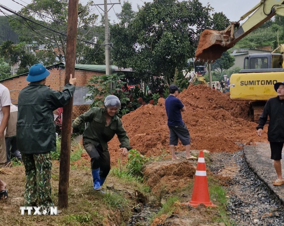 Lực lượng chức năng cùng thiết bị cơ giới triển khai công tác cứu hộ, giải tỏa hiện trường. (Ảnh: TTXVN phát)