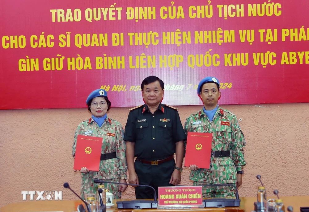 Thượng tướng Hoàng Xuân Chiến, Thứ trưởng Quốc phòng, Tổ trưởng Tổ Công tác liên ngành, Trưởng Ban Chỉ đạo Bộ Quốc phòng về tham gia hoạt động gìn giữ hòa bình Liên hợp quốc trao Quyết định của Chủ tịch nước cho thượng tá Nguyễn Thị Liên và trung tá Nguyễn Đức Doanh. (Ảnh: Trọng Đức/TTXVN)