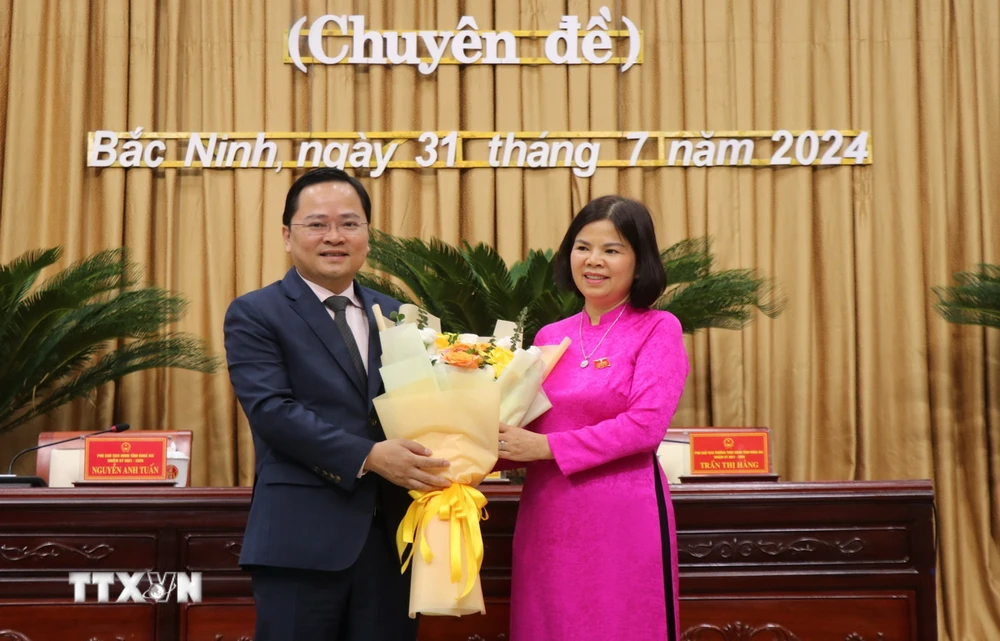 Bí thư Tỉnh ủy Bắc Ninh Nguyễn Anh Tuấn (bên trái) tặng hoa chúc mừng Chủ tịch Hội đồng Nhân dân tỉnh khóa XIX, nhiệm kỳ 2021-2026 Nguyễn Hương Giang. (Ảnh: Thái Hùng/TTXVN)