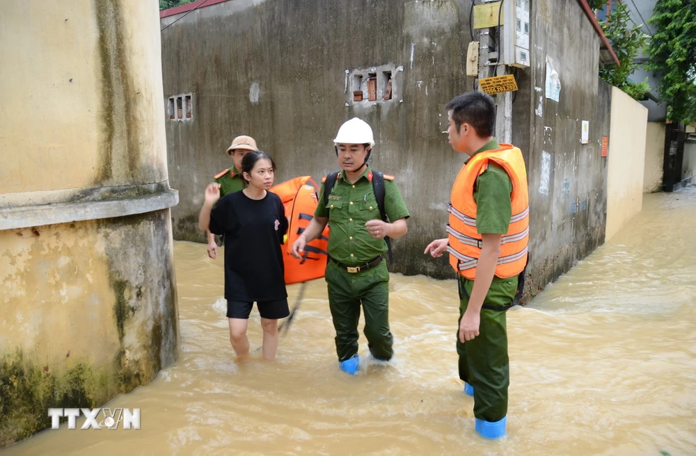 Lực lượng chức năng hỗ trợ người dân đến nơi an toàn. (Ảnh: Đỗ Huyền/TTXVN)