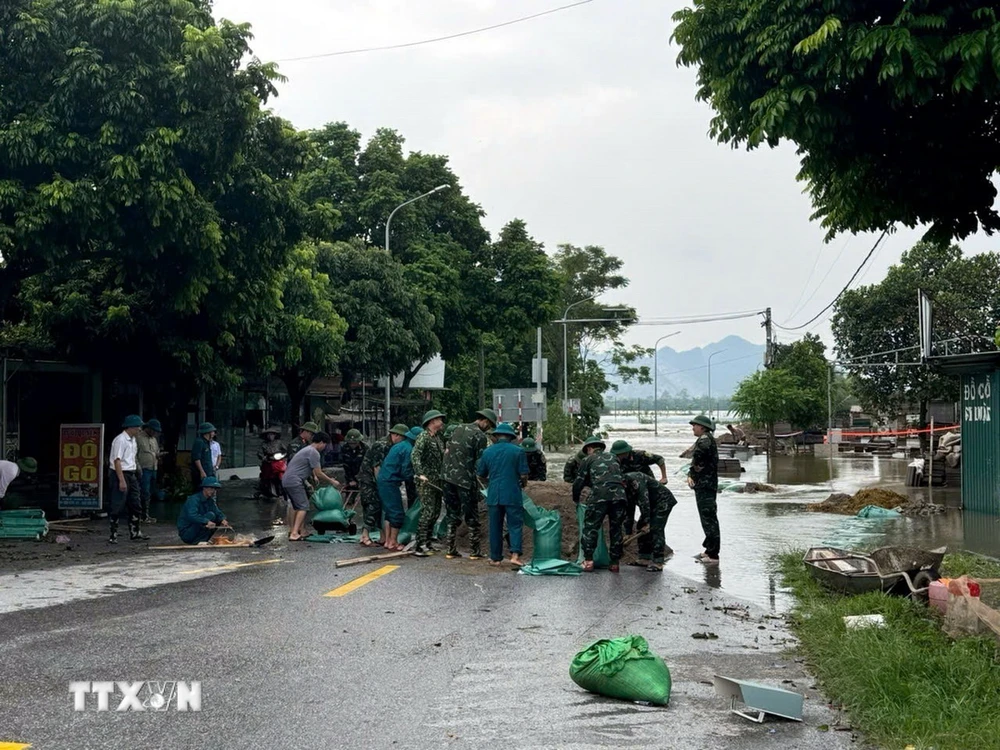 Lượng chức năng xã và huyện Ứng Hòa tập trung ứng phó, đắp tải cát để bảo vệ những điểm xung yếu tại đập tràn Dốc Bồ. (Ảnh: Nguyễn Văn Cảnh/TTXVN)