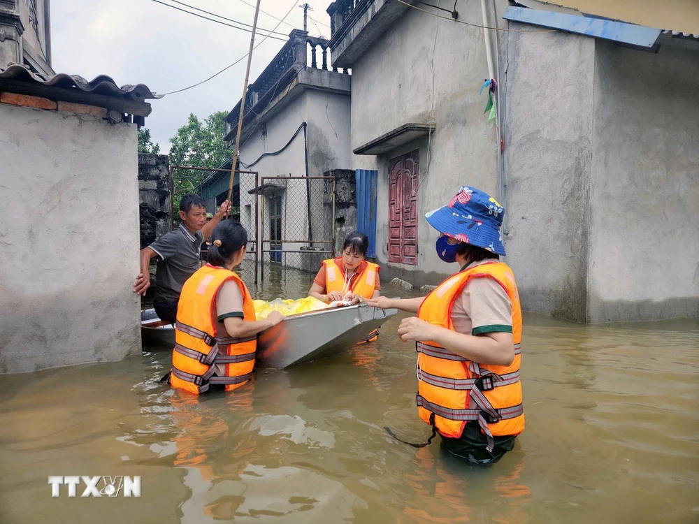 Các cô giáo trường mầm non Thanh Nghị (huyện Thanh Liêm) tổ chức nấu cơm và đi phát cho người dân trong lũ. (Ảnh: Đại Nghĩa/TTXVN)