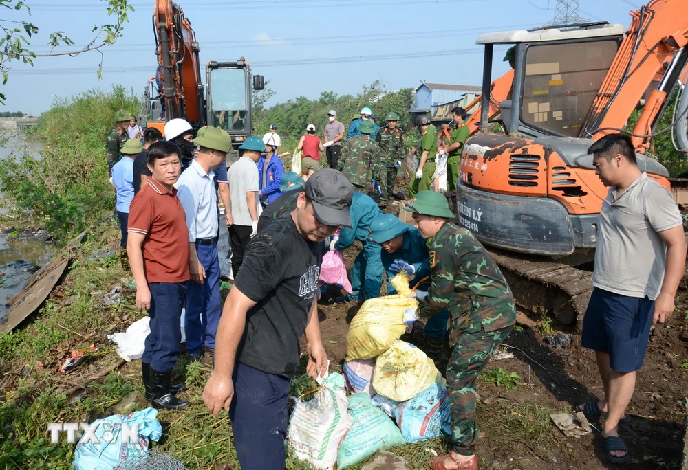 Người dân cùng lực lượng chức năng khắc phục sự cố công trình thủy lợi Ngũ Huyện Khê. (Ảnh: TTXVN phát)