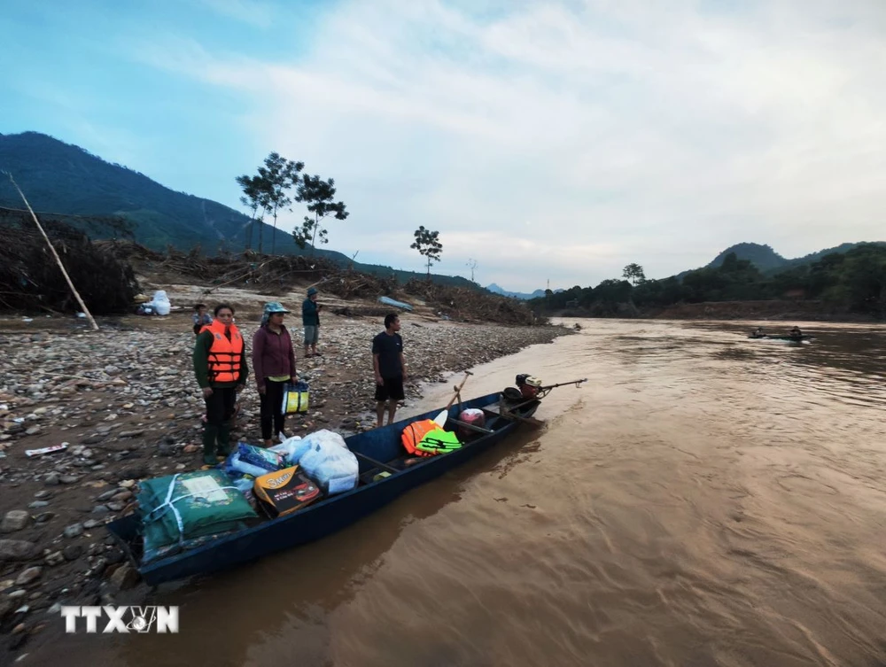 Các tình nguyện viên di chuyển bằng xuồng đến trao hỗ trợ cho người dân bản Cuông 2. (Ảnh: Phùng Nam Sương/TTXVN)