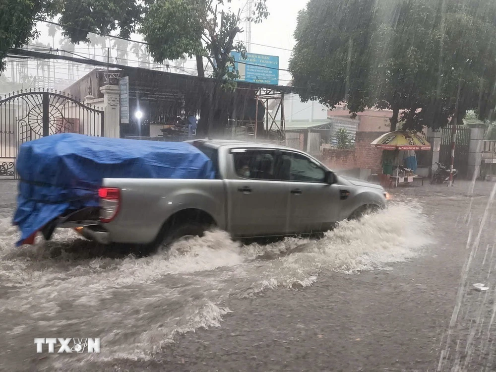 Xe cộ di chuyển khó khăn tại điểm ngập trên đường Cách Mạng Tháng Tám, giáp ranh giữa thành phố Thủ Dầu Một và thành phố Thuận An, tỉnh Bình Dương. (Ảnh: TTXVN phát)