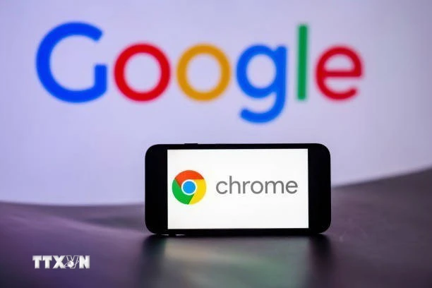 Biểu tượng Chrome trên màn hình điện thoại và biểu tượng Google (phía sau). (Ảnh: Getty Images/TTXVN)