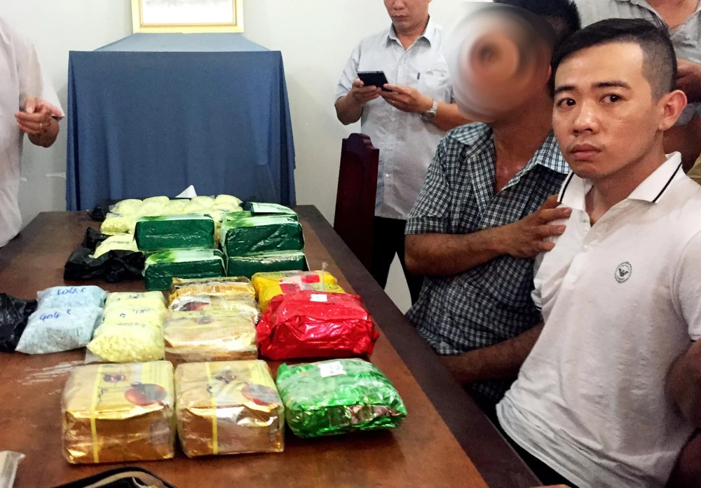 Du Quốc Cường (áo trắng bìa phải, sinh năm: 1990, đăng ký thường trú: 117 Hồng Bàng, Tân Lập, thành phố Nha Trang, tỉnh Khánh Hòa) bị bắt quả tang cùng nhiều ma túy. (Ảnh: Công Mạo/TTXVN)