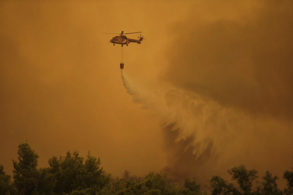 Trực thăng phun nước dập lửa cháy rừng ở gần làng Makrymalli trên đảo Evia, Hy Lạp, ngày 13/8/2019. (Ảnh: THX/TTXVN)