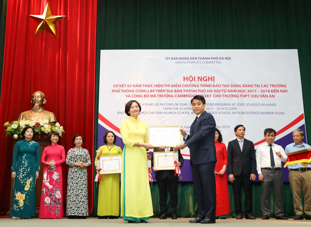 Chủ tịch Ủy ban Nhân dân thành phố Hà Nội Nguyễn Đức Chung tặng Bằng khen cho các tập thể có thành tích trong thực hiện thí điểm chương trình đào tạo song bằng. (Ảnh: Thanh Tùng/TTXVN)