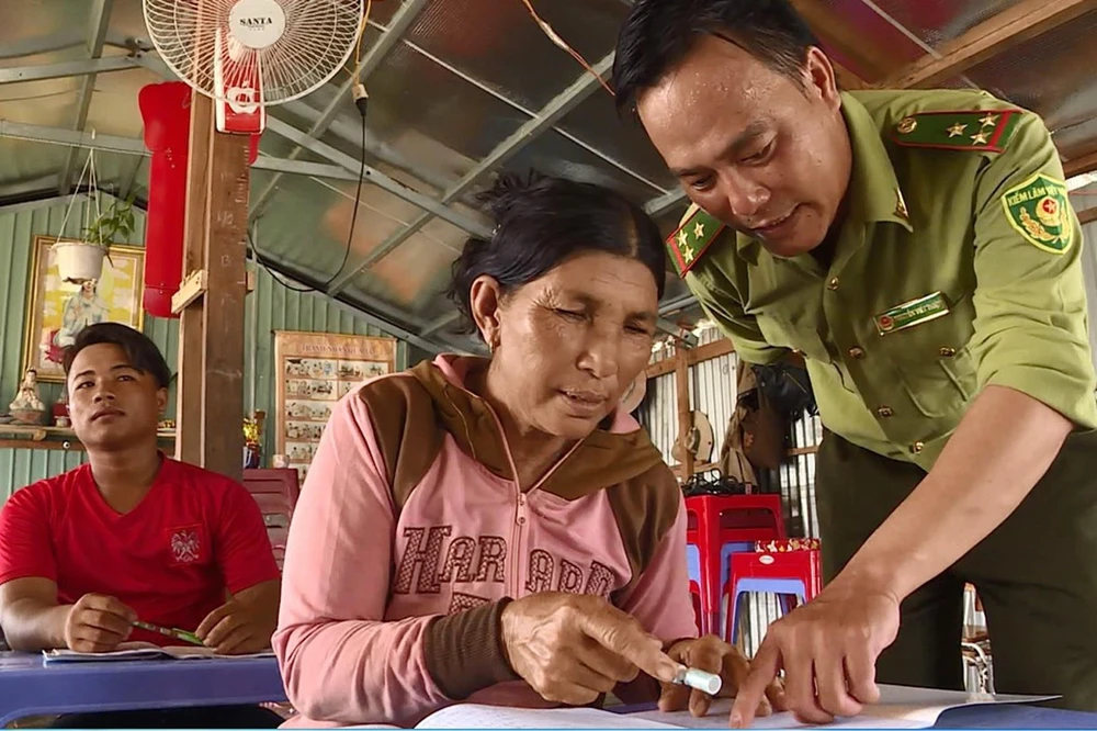 Người dân được chỉ bảo tận tình từng nét chữ trong lớp dạy chữ cho những người Việt kiều Campuchia lớn tuổi trên lòng hồ Trị An. (Ảnh: Lê Xuân/TTXVN)