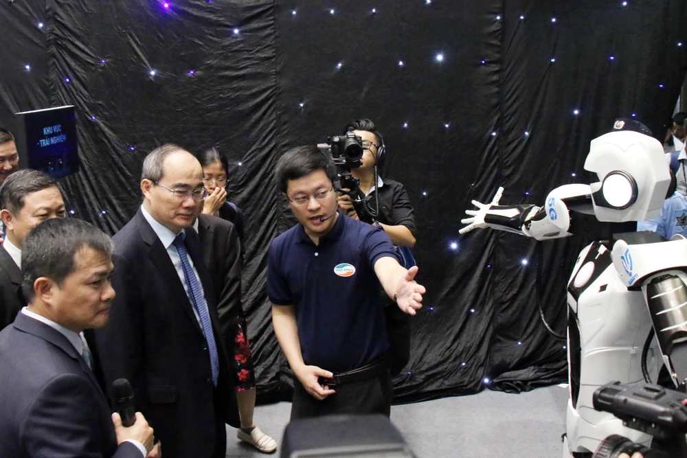 Bí thư Thành ủy Thành phố Hồ Chí Minh Nguyễn Thiện Nhân nghe giới thiệu về robot mô phỏng các động tác được điều khiển từ xa qua sóng 5G. (Ảnh: Tiến Lực/TTXVN)