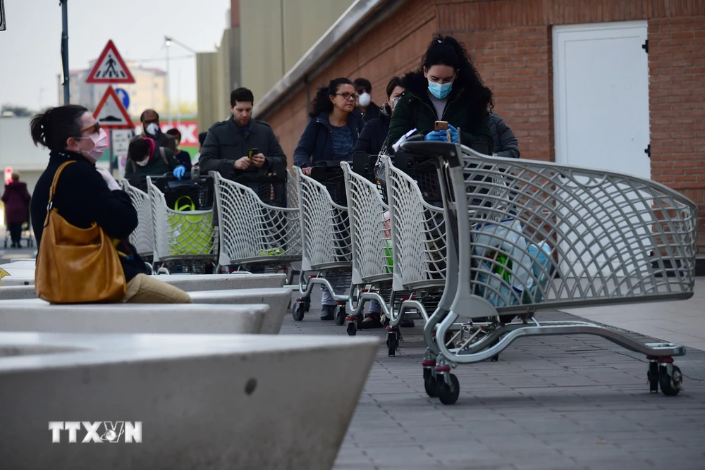 Người dân xếp hàng chờ đợi bên ngoài một siêu thị ở Bologna, Italy ngày 20/3/2020, trong bối cảnh dịch COVID-19 lan rộng. (Ảnh: THX/TTXVN)