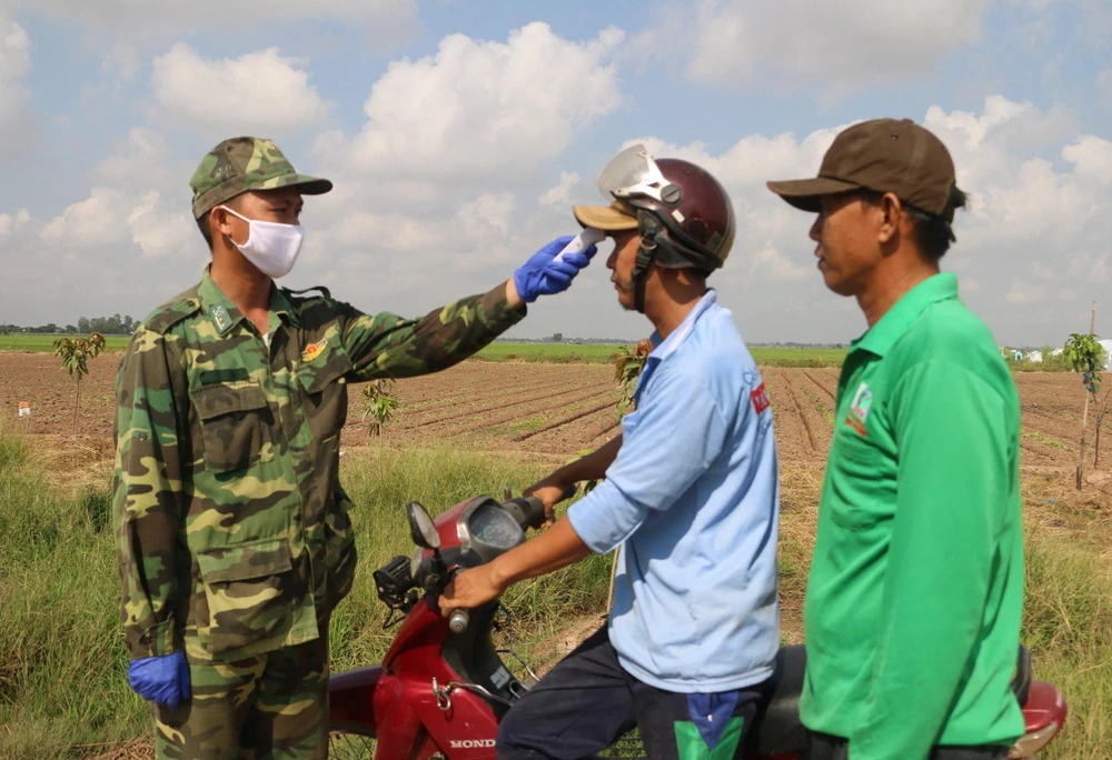 Cán bộ chiến sỹ Đồn Biên phòng quốc tế Vĩnh Xương - Bộ đội Biên phòng tỉnh An Giang tuyên truyền và phát khẩu trang vải người dân khu vực biên giới. (Ảnh: Công Mạo./TTXVN)