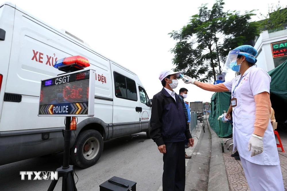 Nhân viên y tế kiểm tra thân nhiệt cho tài xế tại chốt kiểm soát phía Bắc cầu Chương Dương hướng vào nội thành Hà Nội. (Ảnh: Minh Quyết/TTXVN)