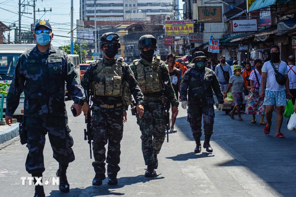 Cảnh sát tuần tra nhắc nhở người dân về các biện pháp phòng tránh dịch COVID-19 tại một chợ ở Manila, Philippines. (Ảnh: AFP/TTXVN)