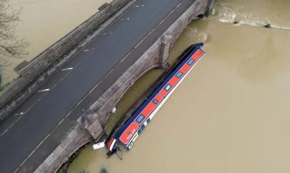 Một chiếc thuyền bị mắc kẹt tại cây cầu đường bộ bắc qua sông Soar ở Barrow sau trận mưa lũ. (Nguồn: Getty Images)
