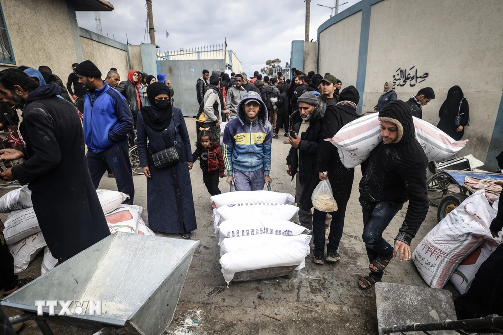 Người tị nạn Palestine nhận lương thực cứu trợ từ UNRWA ở Dải Gaza, ngày 28/1. (Ảnh: AFP/TTXVN)