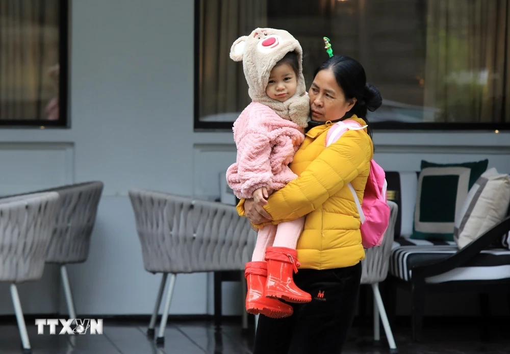 Một em bé được mẹ mặc áo ấm khi ra ngoài đường. (Ảnh: Tuấn Anh/TTXVN)
