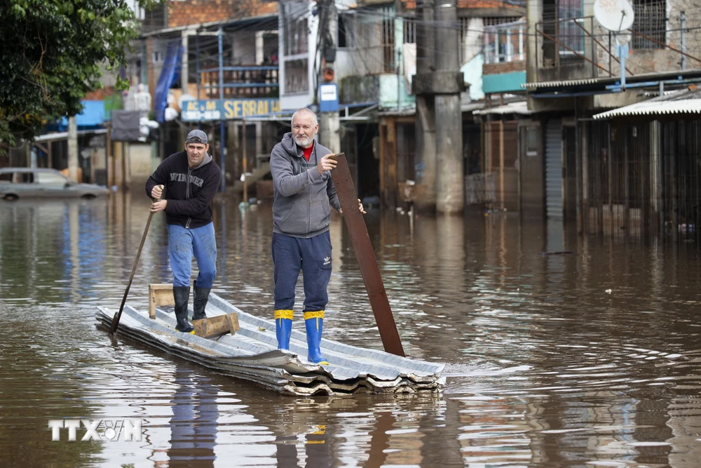 Người dân di chuyển qua vùng ngập lụt tại Porto Alegre, bang Rio Grande do Sul, Brazil, ngày 29/5. (Ảnh: AFP/TTXVN)