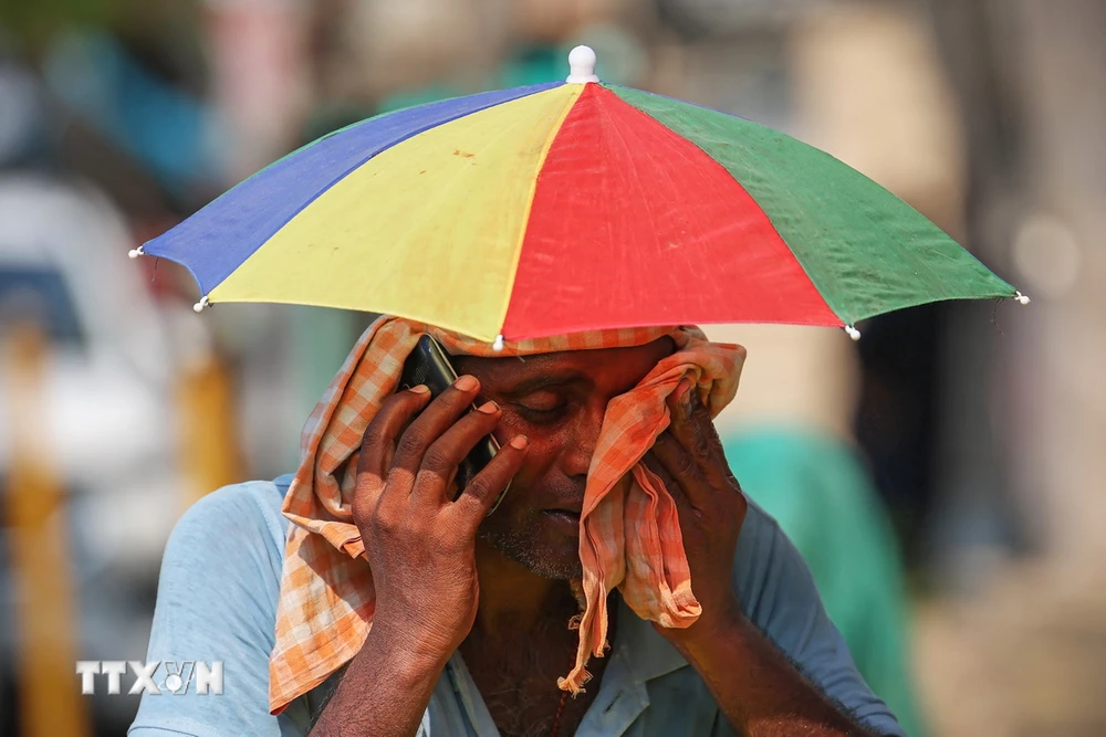 Người dân che ô và quấn khăn khi di chuyển ngoài trời trong ngày nắng nóng tại Varanasi, Ấn Độ. (Ảnh: AFP/TTXVN)