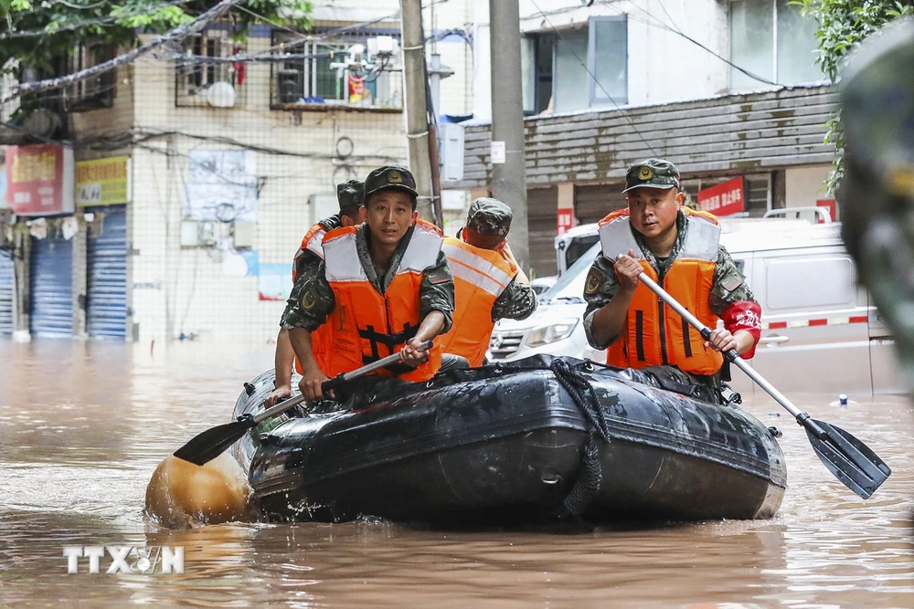 Cảnh sát Trung Quốc giúp sơ tán người dân khỏi các khu vực ngập lụt. (Ảnh: AFP/TTXVN)