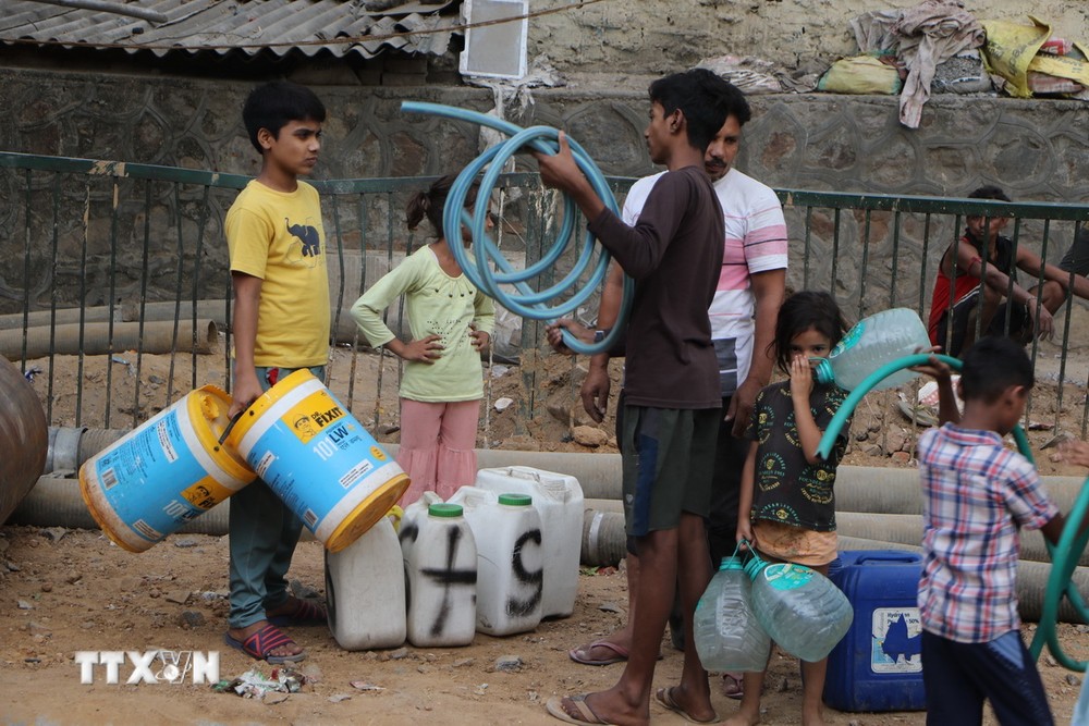Người dân chuẩn bị đồ chứa nước và ống hút nước trước khi xe bồn chở nước của chính phủ tới. (Ảnh: Ngọc Thúy/TTXVN)