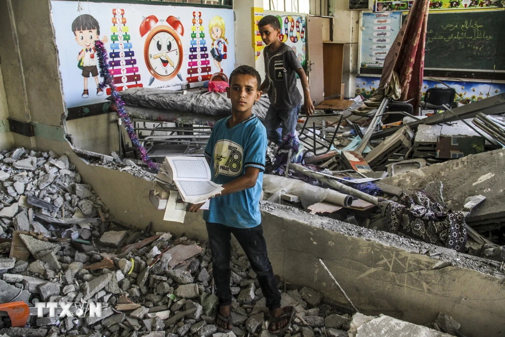 Trẻ em bên đống đổ nát của trường học bị trúng không kích của Israel tại thành phố Gaza ngày 25/6. (Ảnh: THX/TTXVN)