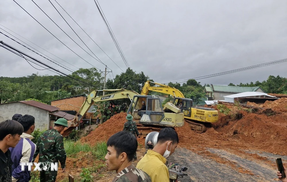 Lực lượng chức năng cùng thiết bị cơ giới triển khai công tác cứu hộ, giải tỏa hiện trường vụ sạt lở. (Ảnh: TTXVN phát)