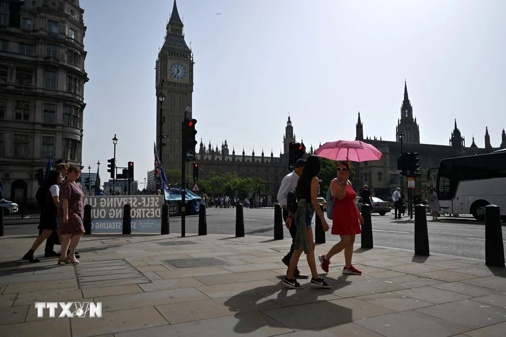 Người dân di chuyển dưới trời nắng nóng tại London, Anh. (Ảnh: AFP/TTXVN)