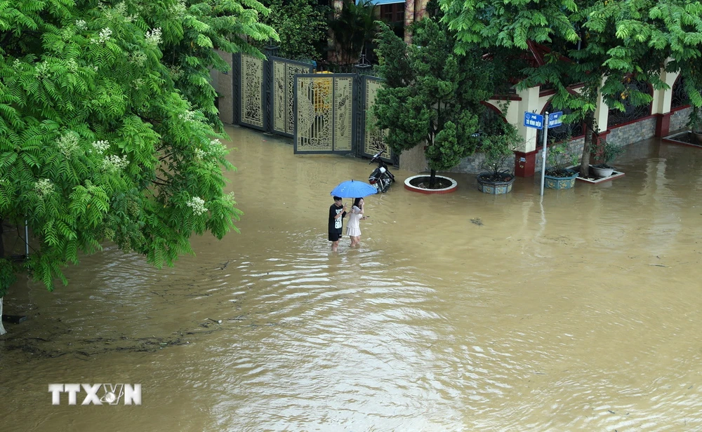 Đường Phạm Văn Xảo, phường Lào Cai, thành phố Lào Cai bị lũ tràn vào, ngập trong biển nước lúc 11g30 ngày 9/9 khiến người dân đi lại khó khăn. (Ảnh: Quốc Khánh/TTXVN)