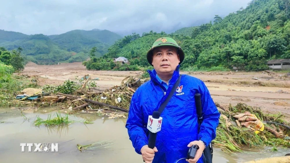 Phóng viên Hồng Ninh, Cơ quan thường trú Lào Cai tác nghiệp khu vực thảm họa lũ quét tại làng Nủ, xã Phúc Khánh, huyện Bảo Yên (Lào Cai). (Ảnh: TTXVN)