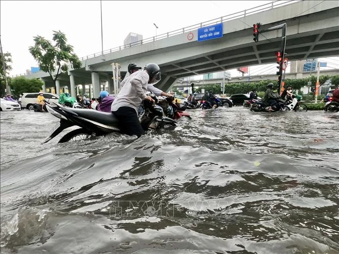 Nước ngập đến hơn nửa mét khiến người dân TP Hồ Chí Minh di chuyển hết sức khó khăn. (Nguồn: TTXVN)